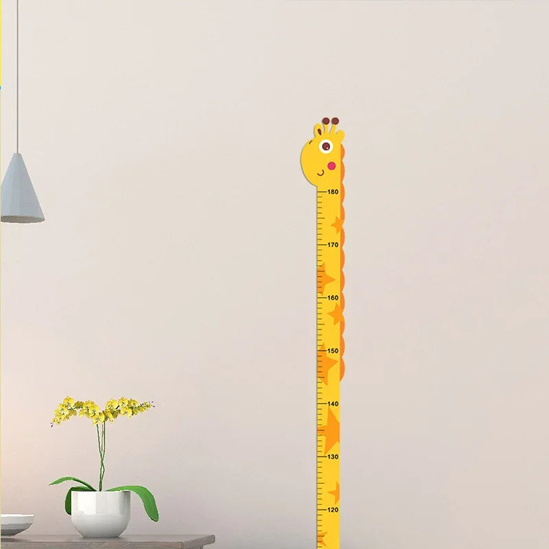 Giraffe growth chart wall decal with height markings on nursery wall above table with yellow flowers.
