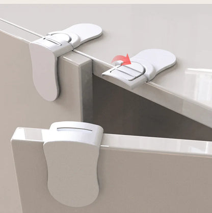 White baby safety drawer locks demonstrating open position and unlocking mechanism on cabinet edges.