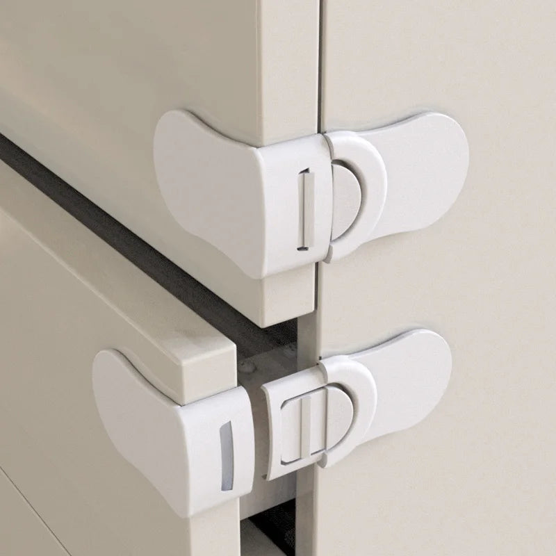 White baby safety drawer locks installed on corner of cabinet doors for childproofing.