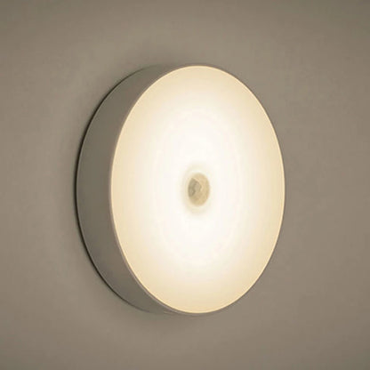 Warm light rechargeable motion sensor night light glowing softly on wall.