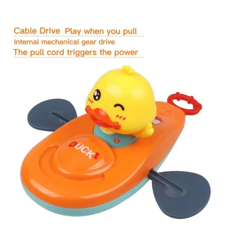 Close-up of yellow duck on orange kayak bath toy with red pull cord and cable drive text.