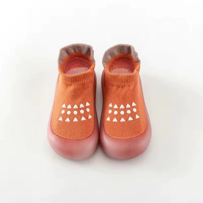 Orange breathable baby walking shoes with soft sole and white anti-slip pattern front view.