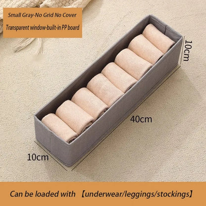 Small gray foldable fabric storage box with clear window for baby clothes storage.