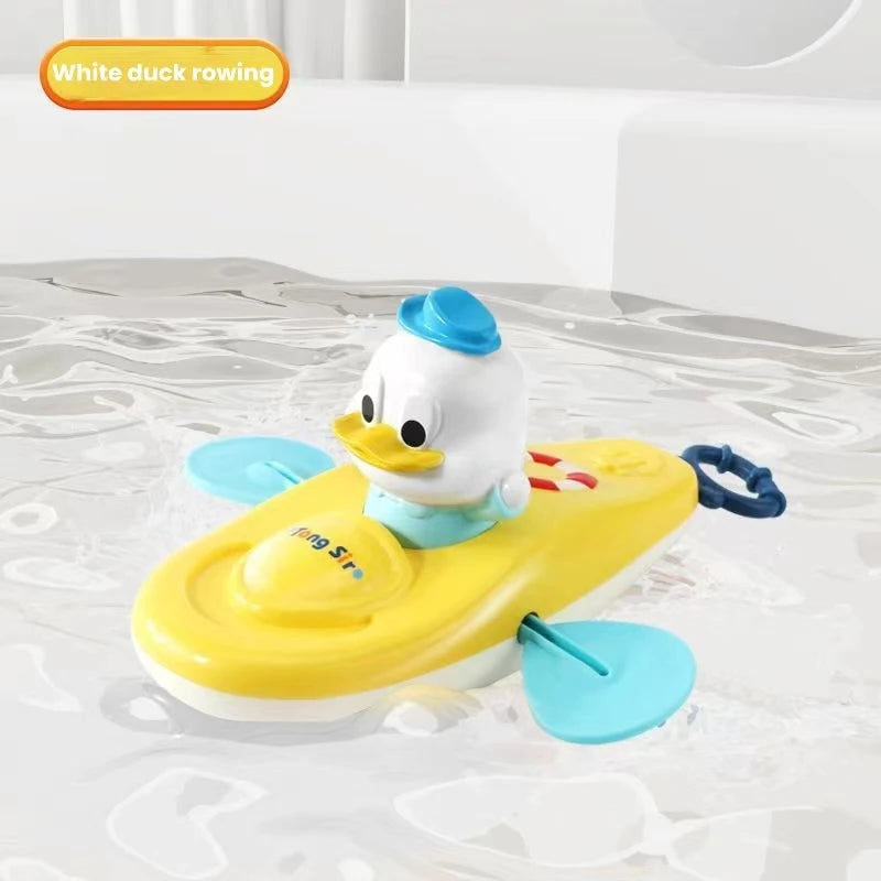White duck kayak bath toy with blue paddles and blue hat floating in water.