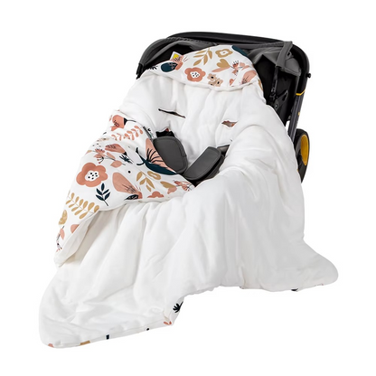 Hooded baby wrap blanket with floral and leaf print lining in stroller.