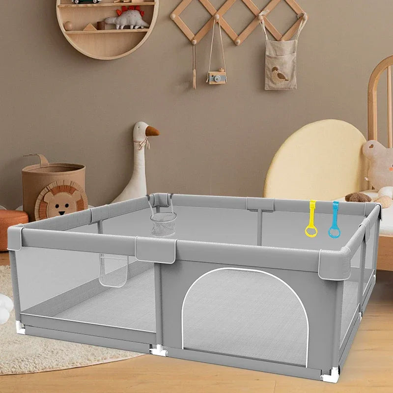 Gray baby playpen with mesh sides and pull rings in nursery setting.