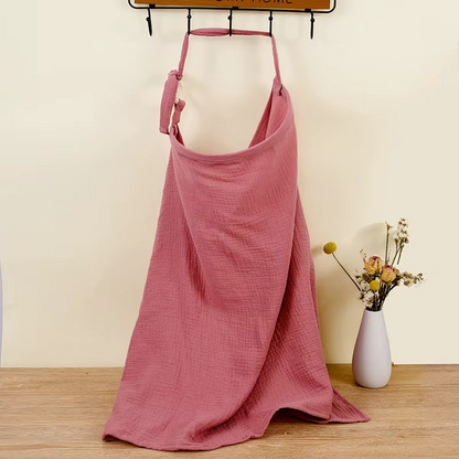 Dark pink breathable muslin nursing cover hanging with adjustable strap and wooden ring.
