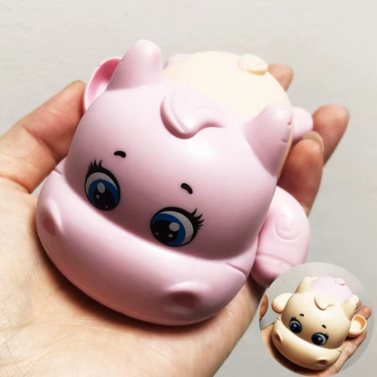 Pink calf wind-up bath toy held in hand showing face and body.