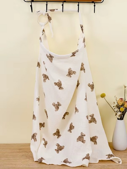 White breathable muslin nursing cover with teddy bear print hanging with adjustable strap and ring.