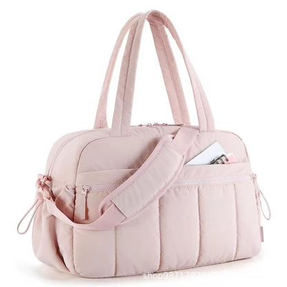 Pink waterproof diaper travel bag with shoulder strap and front zippered pocket.
