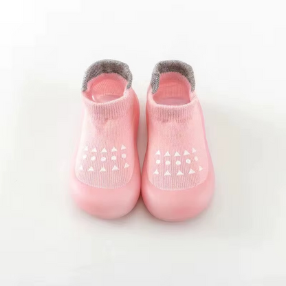 Pink breathable baby walking shoes with soft sole and white anti-slip pattern front view.