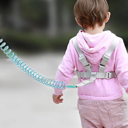 Child in pink hoodie wearing blue toddler anti-lost safety harness with spring leash attached to wrist.