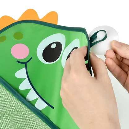 Hands attaching suction cup to green dinosaur bath toy storage mesh bag corner.