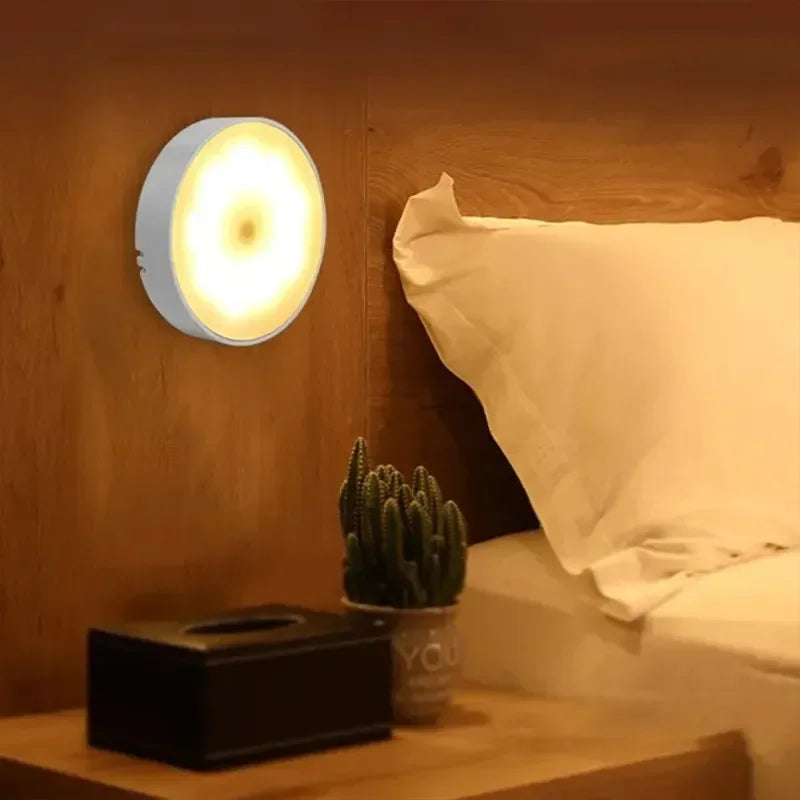 Warm light rechargeable night light mounted on bedroom wall near bedside table.