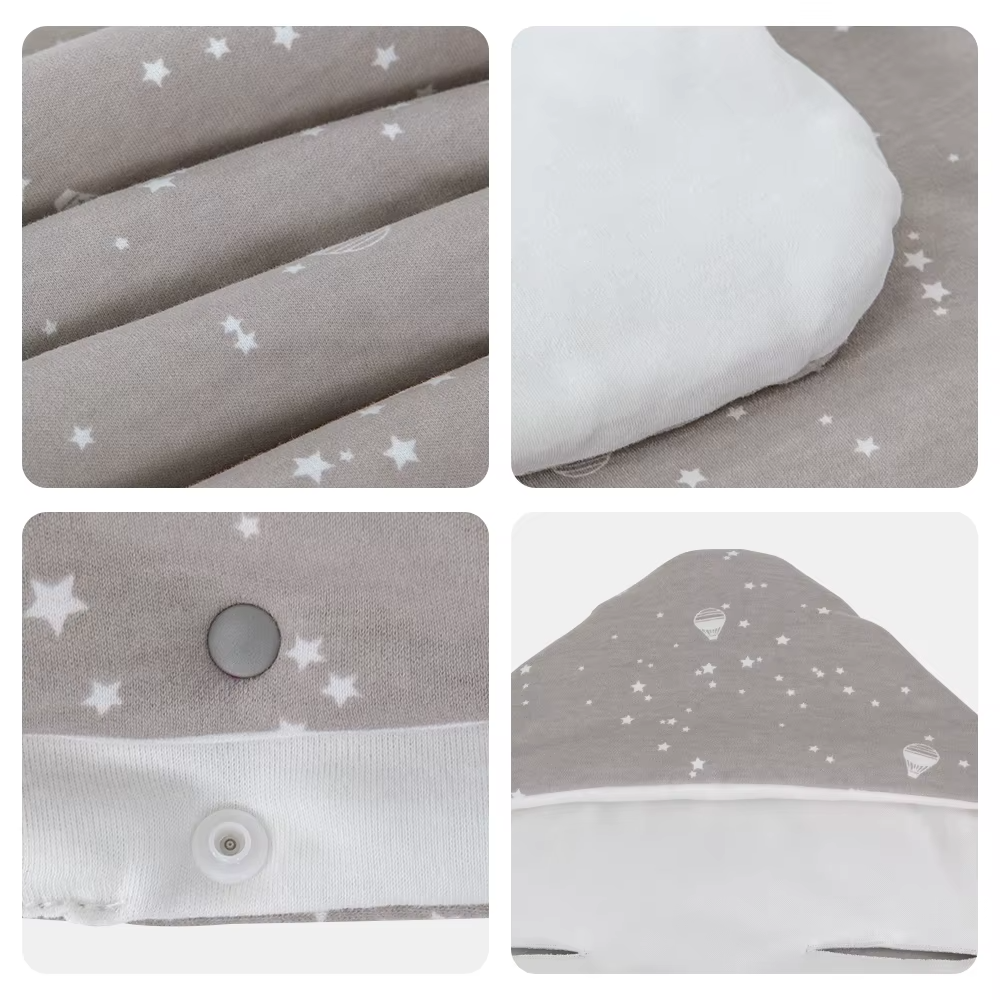 Close-up details of grey star print fabric, white lining, snap button, and hood of baby wrap blanket.