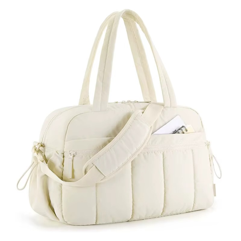 Side view of beige waterproof diaper travel bag with shoulder strap and front zippered pocket.