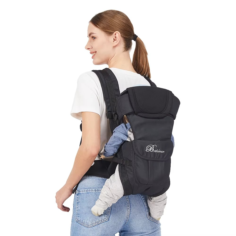 Rear view of black ergonomic baby carrier worn on back with baby facing inward.