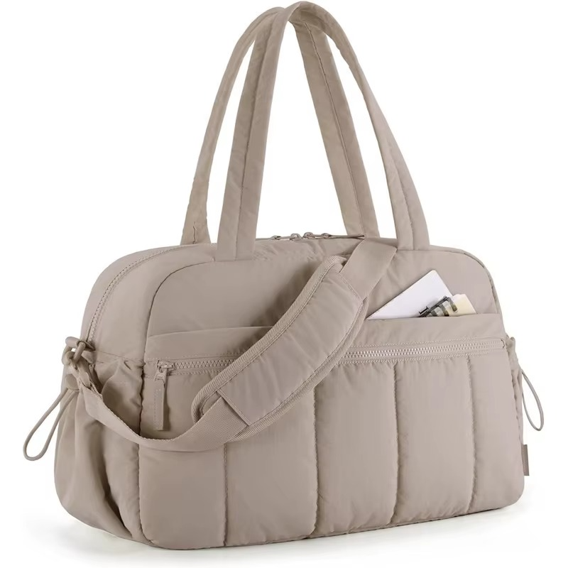 Beige waterproof diaper travel bag with shoulder strap and front and side pockets.