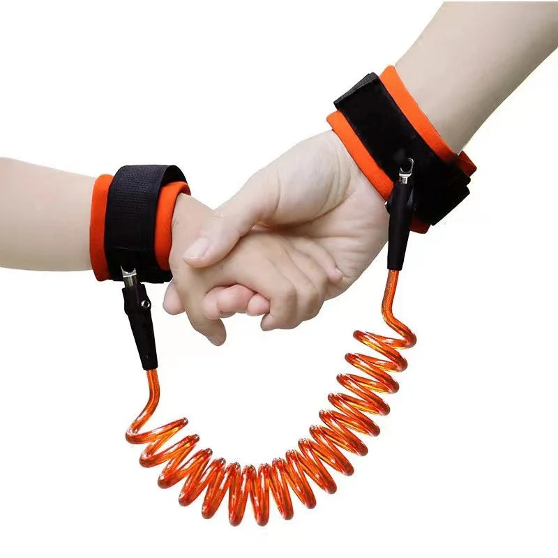 Orange toddler safety leash worn on wrists of adult and child holding hands.