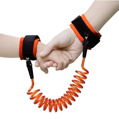 Orange toddler safety leash worn on wrists of adult and child holding hands.