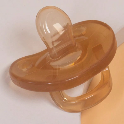 Close-up of light brown silicone baby pacifier with flat nipple and handle.