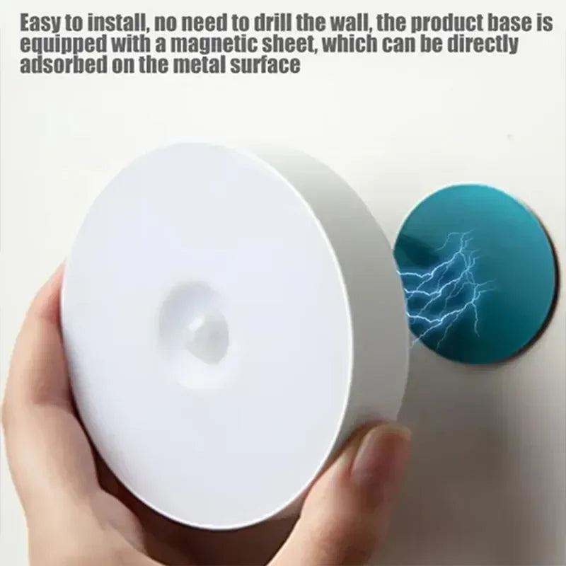 Hand holding rechargeable night light near magnetic mounting plate for easy wall attachment.