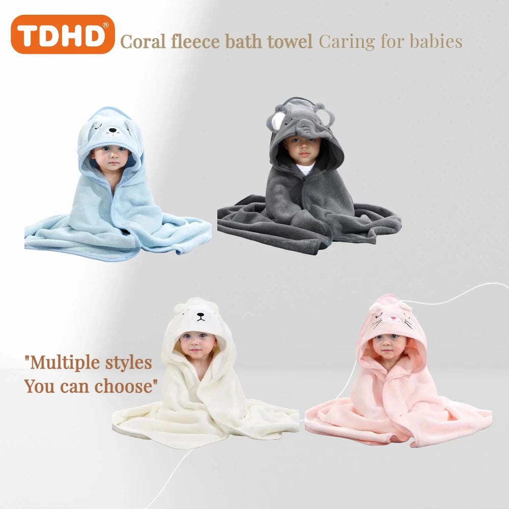 Baby wrapped in brown deer animal hooded baby bath towel with embroidered face and antlers sitting on white rug.