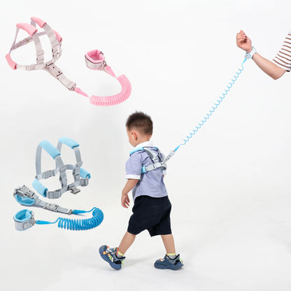 Toddler wearing blue anti-lost safety harness with spring leash wrist strap and pink harness set shown.