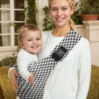 Houndstooth adjustable baby carrier wrap worn sling style with baby held by woman.