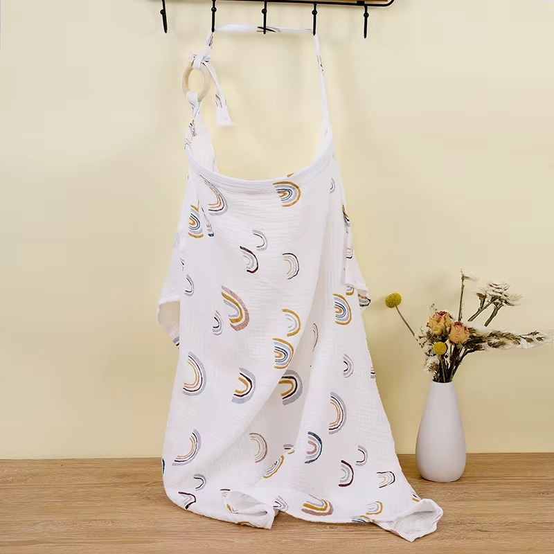 White breathable muslin nursing cover with multicolor rainbow print hanging with adjustable strap and ring.