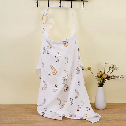 White breathable muslin nursing cover with multicolor rainbow print hanging with adjustable strap and ring.