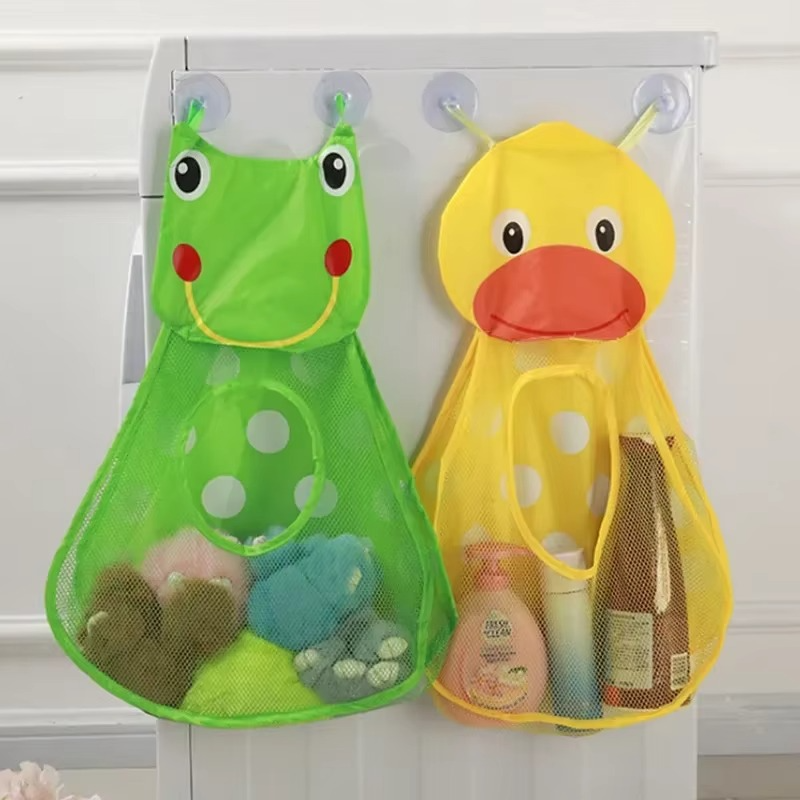 Green frog and yellow duck bath toy storage mesh bags hanging on suction cups on cabinet door.