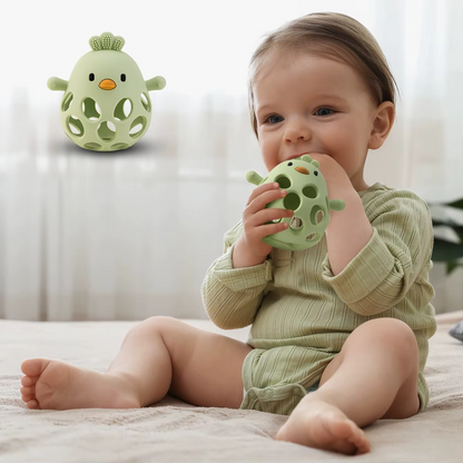Baby holding olive green silicone baby teether rattle while sitting on floor.