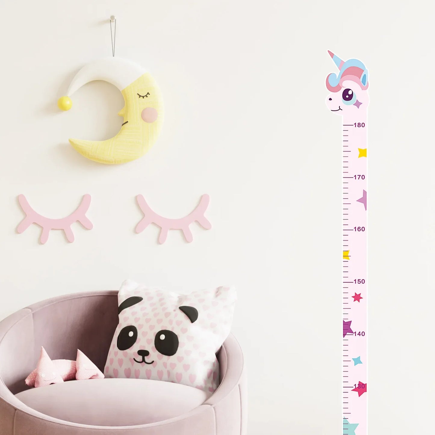 Pink unicorn growth chart decal on nursery wall with moon and eyelash decor above pink chair.