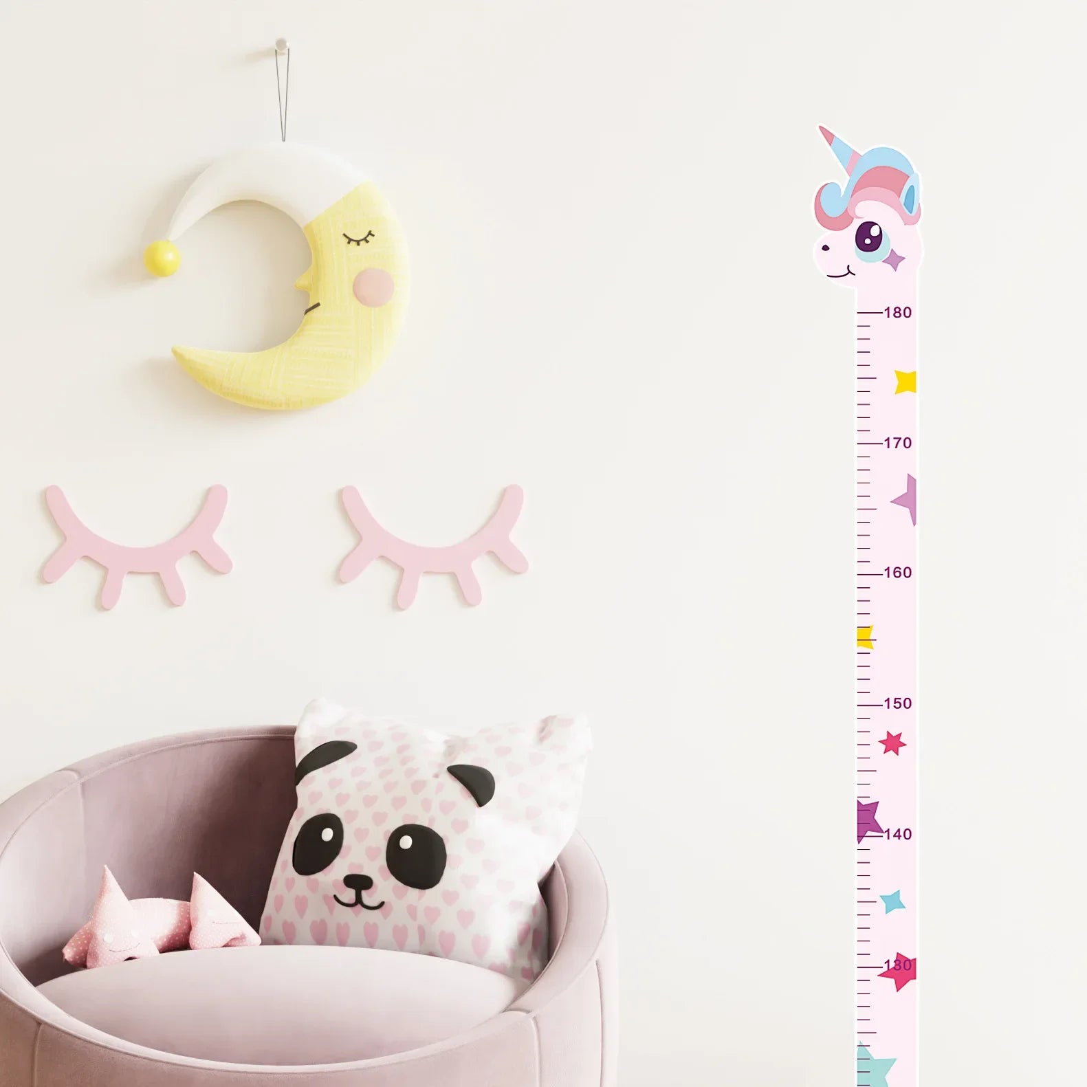 Pink unicorn growth chart decal on nursery wall with moon and eyelash decor above pink chair.