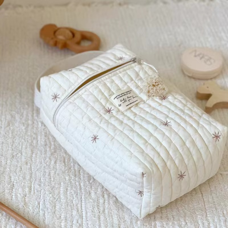 Quilted Diaper Caddy Bag Snowflake variant flat on white fabric with wooden toys and compact.