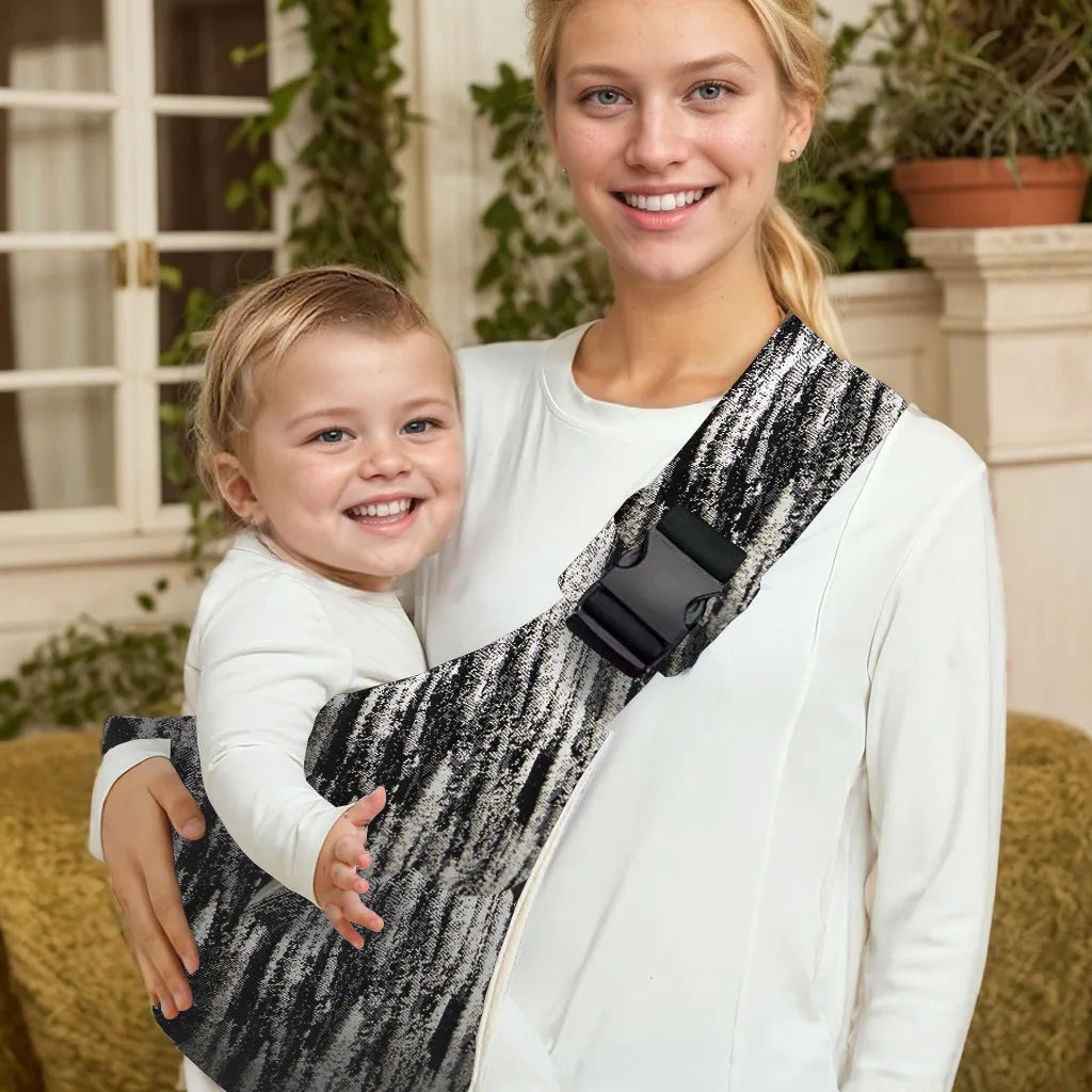 Abstract black and white adjustable baby carrier wrap worn sling style with baby held by woman.