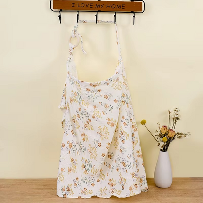 Floral breathable muslin nursing cover hanging with adjustable strap and wooden ring.