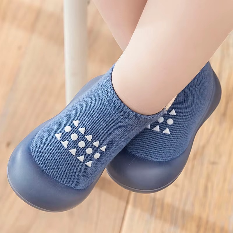 Baby wearing blue breathable walking shoes with soft sole and anti-slip pattern on wooden floor.