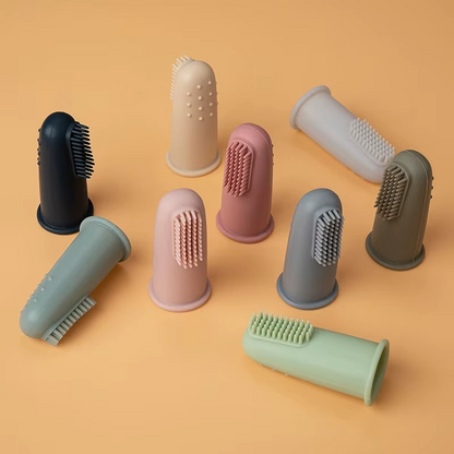 Assorted colors of baby silicone finger toothbrushes displayed on beige background.