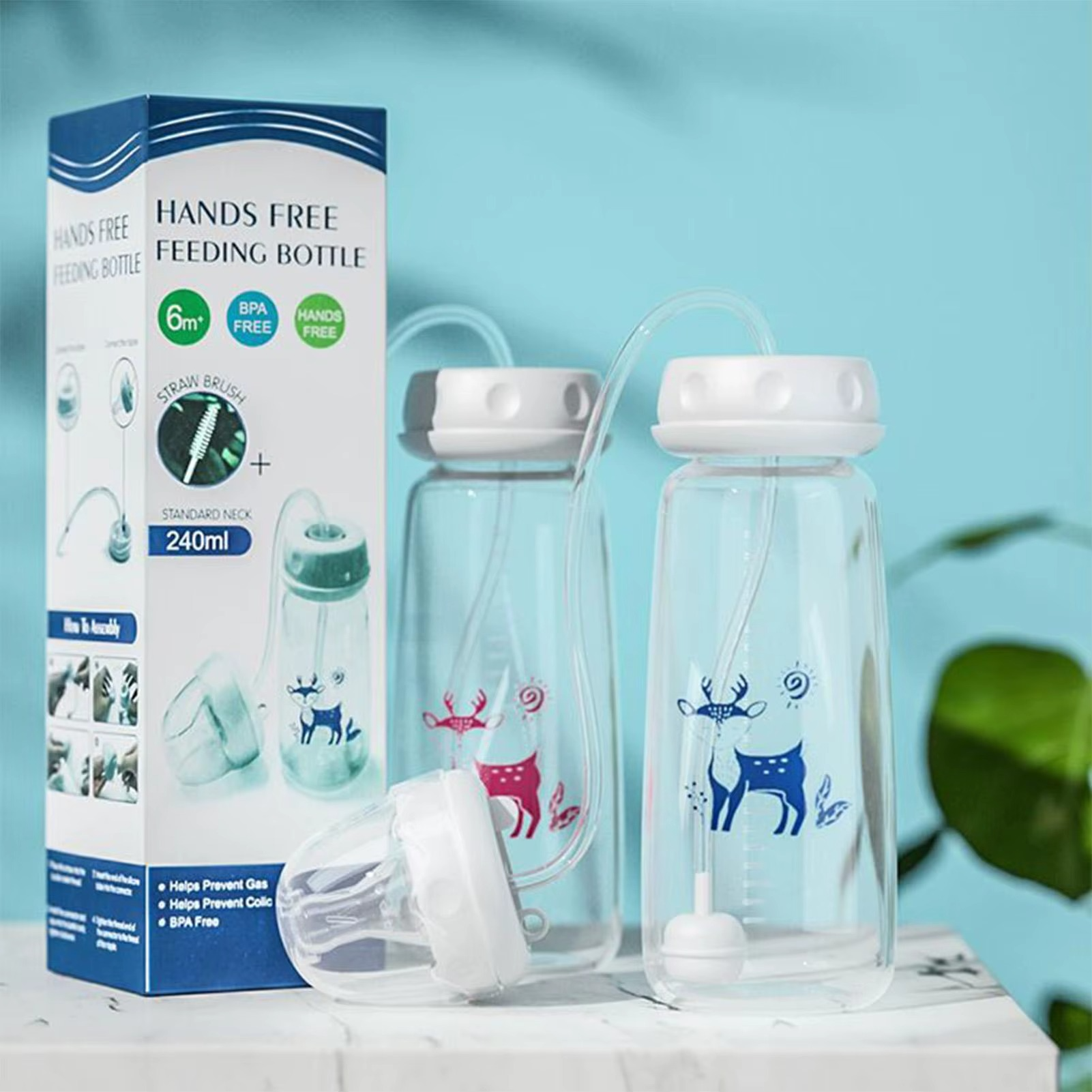 Blue and pink hands-free baby bottles with gravity balls and packaging box on marble surface.