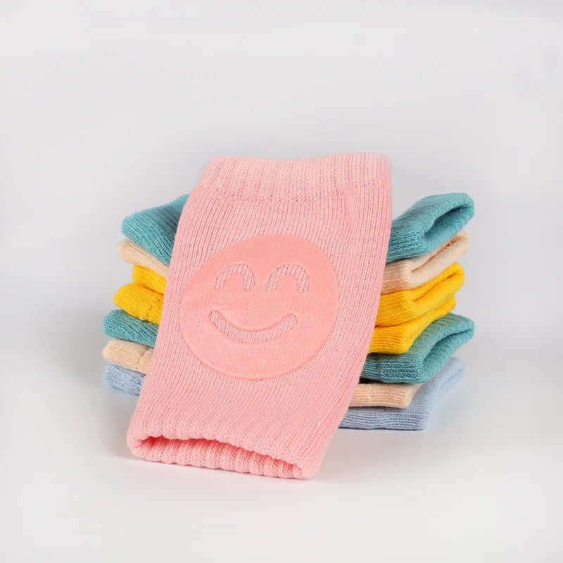Stack of Comfort Crawl baby knee pads in multiple colors with pink pair on top.