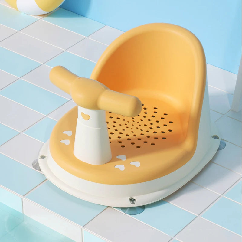 Yellow Comfy Baby Bath Seat on tiled floor with bath ball nearby.