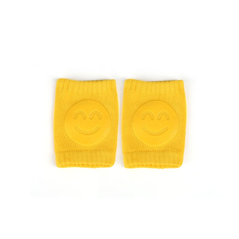 Yellow Comfort Crawl baby knee pads with smiley face grip pads laid flat.