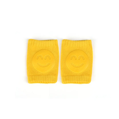 Yellow Comfort Crawl baby knee pads with smiley face grip pads laid flat.