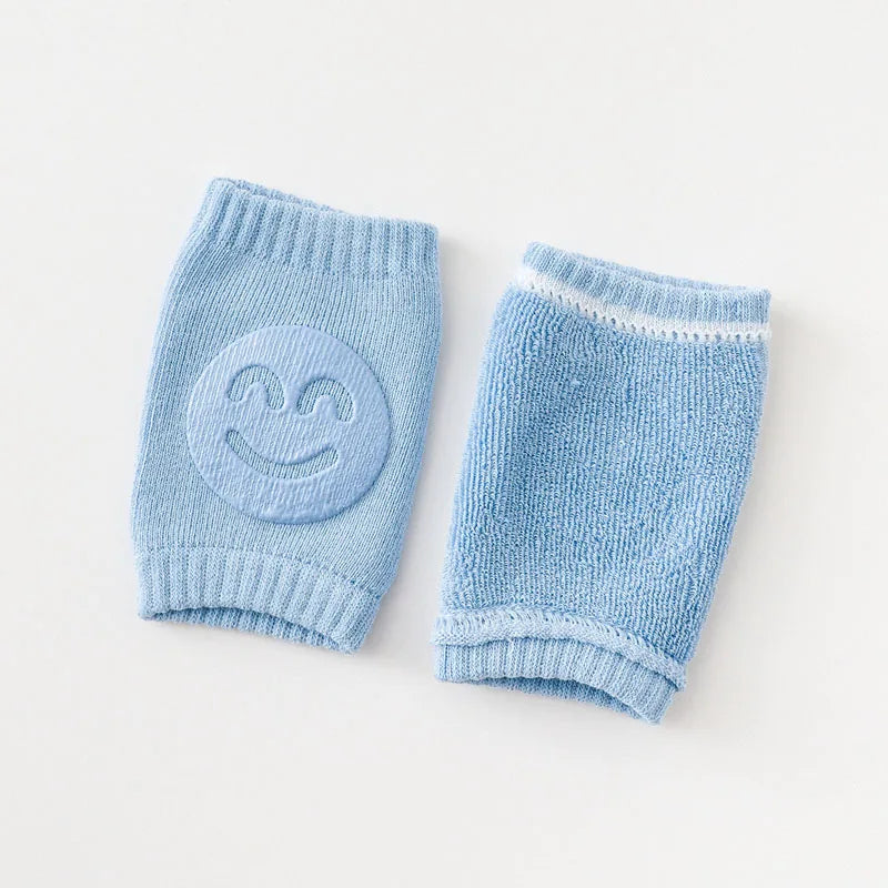 Light blue Comfort Crawl baby knee pads showing front smiley grip and back terry texture.