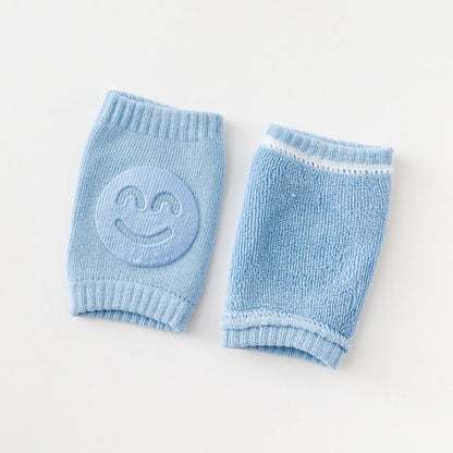 Light blue Comfort Crawl baby knee pads showing front smiley grip and back terry texture.