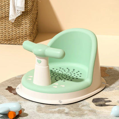 Green Comfy Baby Bath Seat on rug with wicker basket and towel nearby.