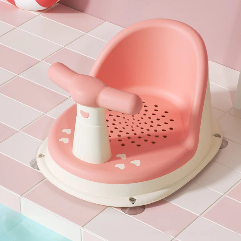 Pink Comfy Baby Bath Seat on tiled floor with bath ball in background.