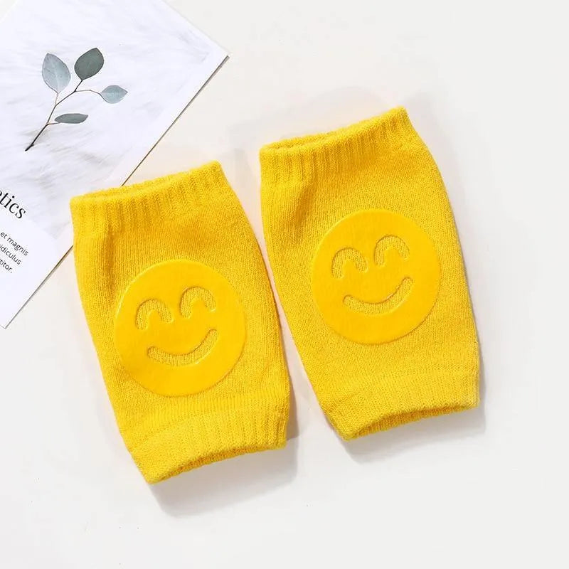 Yellow Comfort Crawl baby knee pads with smiley grip pads on white background with leaf print.